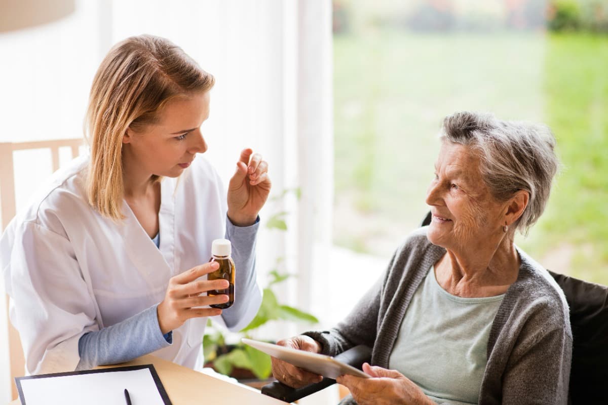 Caregiver explaining medication to an elderly woman.