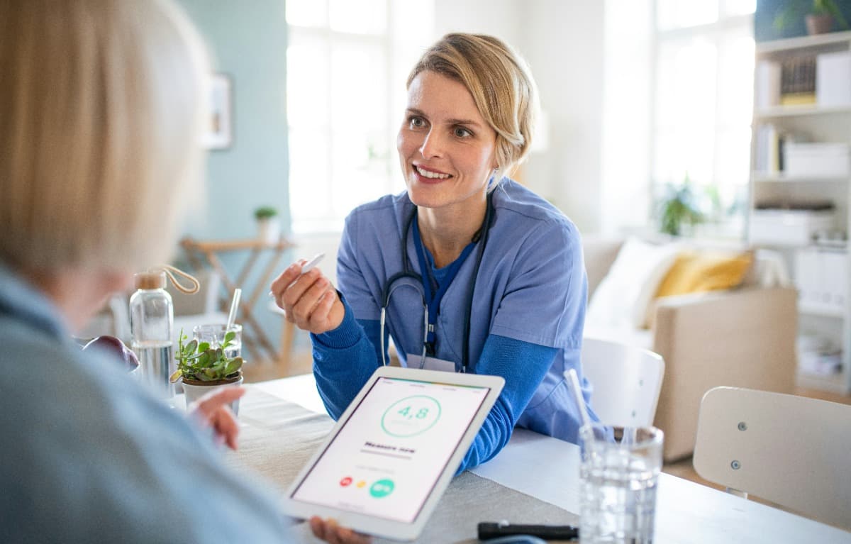 Nurse showing health data on a tablet to an elderly woman.