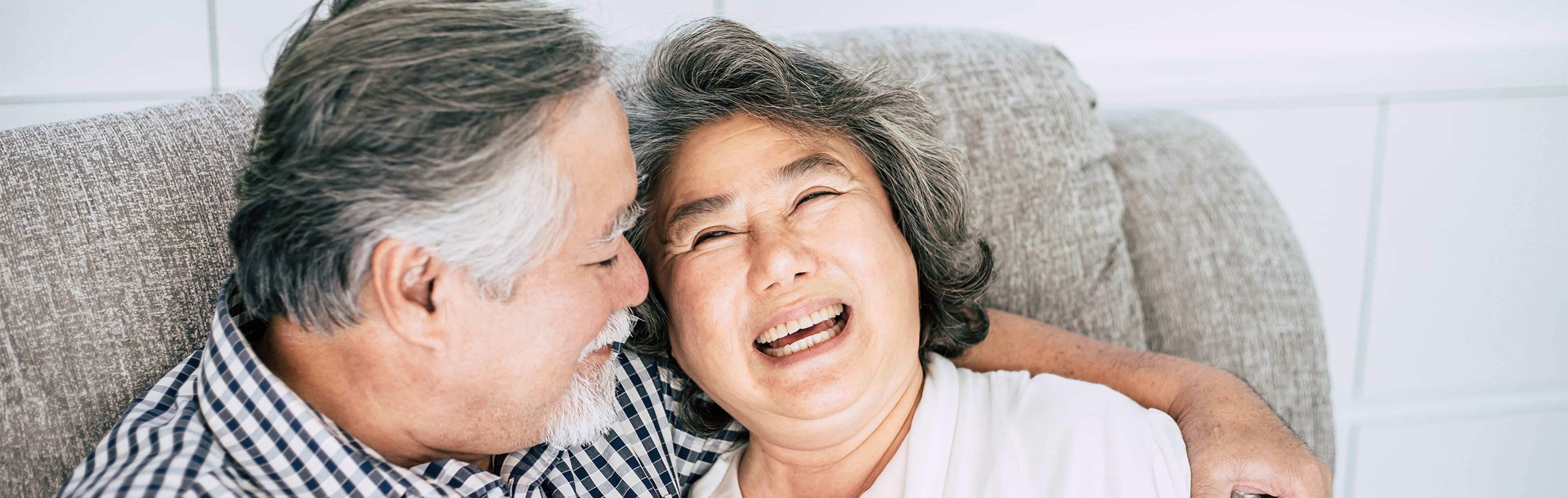 An elderly couple sitting together and laughing with each other