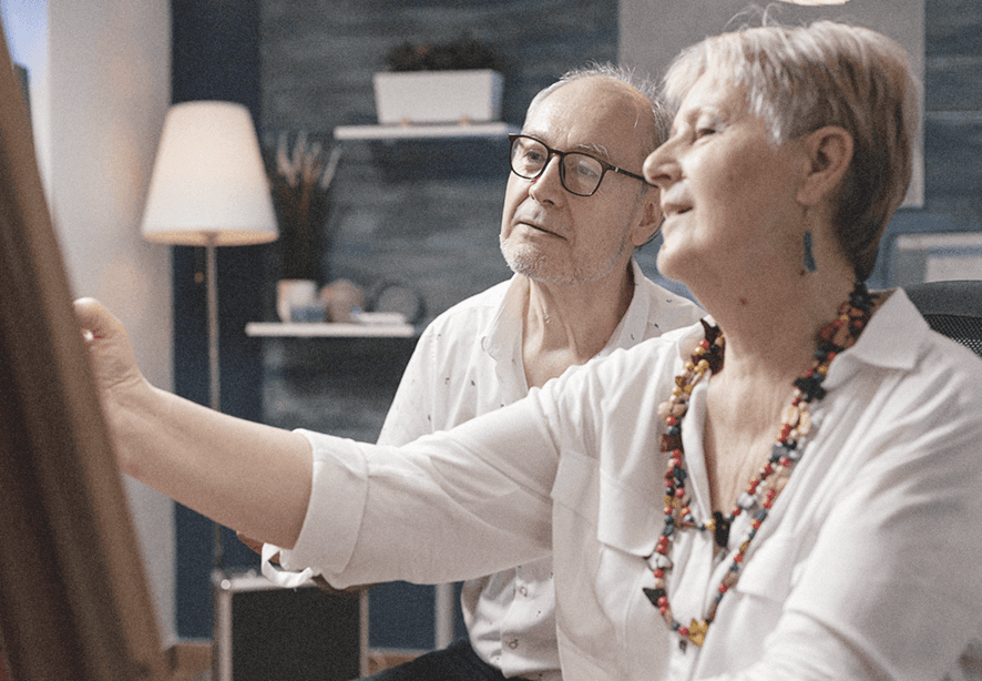 elderly woman sketching while husband watches